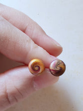 Load image into Gallery viewer, Gold and purple swirl earrings held between finger and thumb