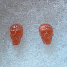 Load image into Gallery viewer, Skull stud earrings in a translucent copper color.