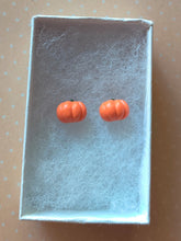 Load image into Gallery viewer, A pair of flat backed, side view, orange pumpkin earrings inside a white paper jewelry box.