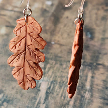 Load image into Gallery viewer, Close up image of a pair of rust brown oak leaf shaped polymer clay earrings on plastic ear hooks