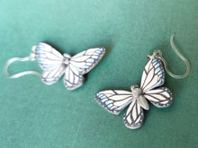 Load image into Gallery viewer, Two white, silver, and blue butterfly earrings with stainless steal jump rings and plastic ear hooks. One is in the foreground is clear and in focus, while the other sits just outside of focal range.