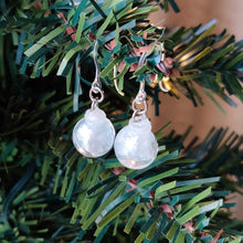 Load image into Gallery viewer, Two miniature Christmas ornament baubles in a clear color with silvery white swirls inside. The earrings are shown hanging from the branch of an artificial Christmas tree.