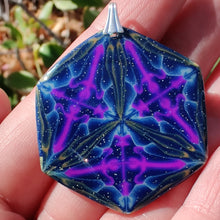 Load image into Gallery viewer, A large hexagonal pendant with a silver colored bail resting in a hand in the sunlight. The pendant is navy blue with veins of gold around the edges and radiating from the center in thirds. There are purple veins in the relative shape of a triangle throughout the pendant.