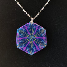 Load image into Gallery viewer, A large hexagonal pendant hanging from a silver colored chain and bail. The pendent is dark blue with purple, gold, and light blue colors radiating out from the center. It is displayed with a black velvet background.