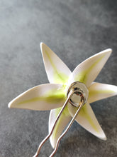Load image into Gallery viewer, An image showing the back of the white lily hair pin. The silver colored bezel and hair pin are visible with the white petals and green veins showing from the back of the flower.