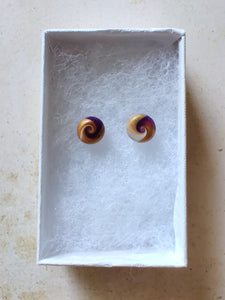 Purple, gold and white swirl earrings inside a white paper jewelry box