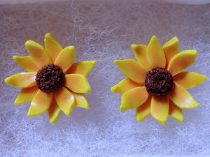 Close up of two sunflower earrings in a white paper jewelry box