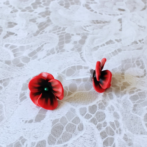 Red and black flower shaped earrings with green metallic centers