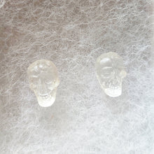 Load image into Gallery viewer, A close up picture of a pair of clear skull stud earrings. 
