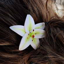 Load image into Gallery viewer, A top view of a white lily pin in a blond hairstyle. 
