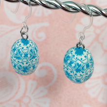 Load image into Gallery viewer, Patterned Easter egg shaped dangle earrings in a blue and white color hanging from a silver wire. 
